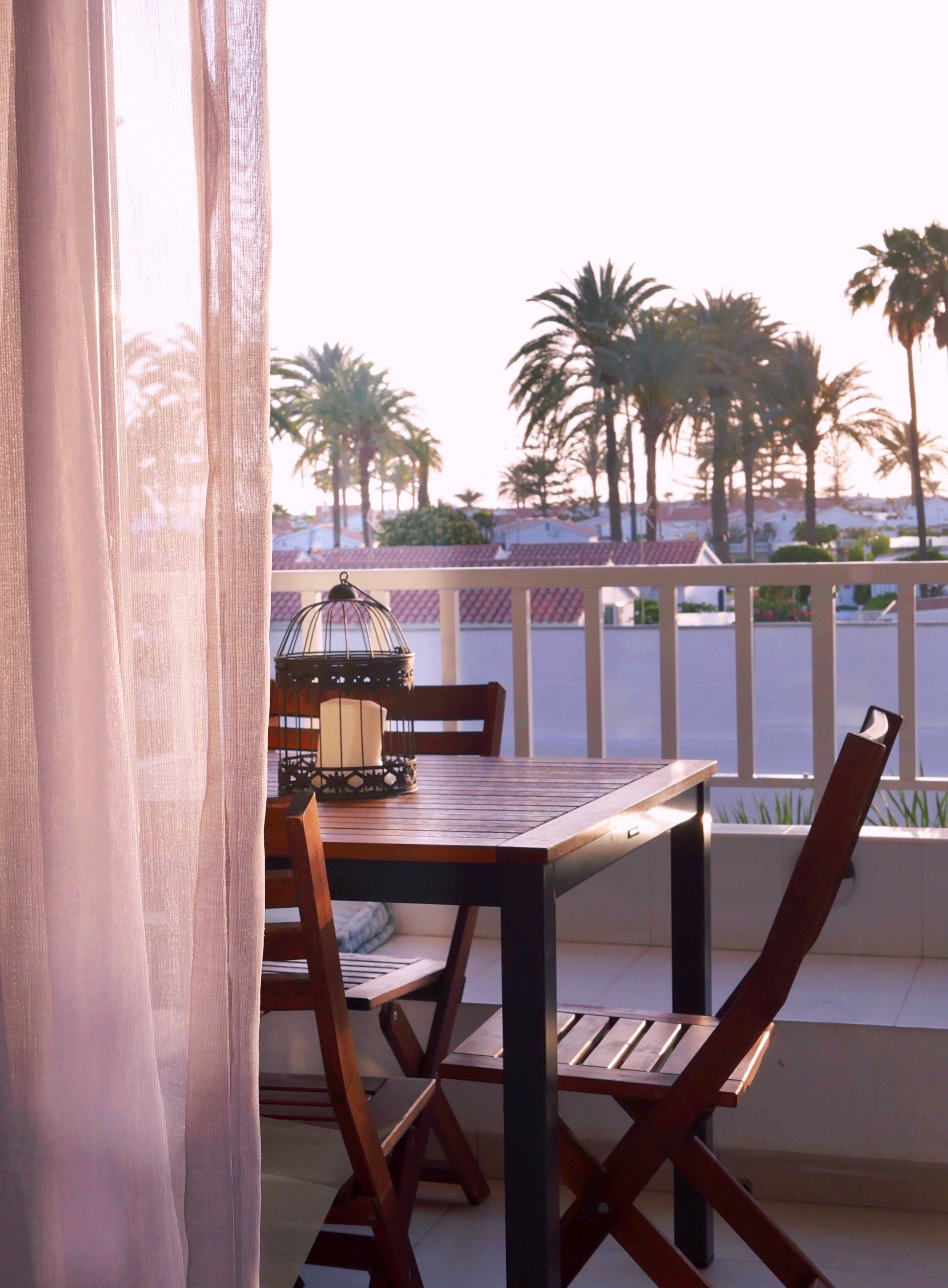 Loggia table and chairs at dusk with palm trees