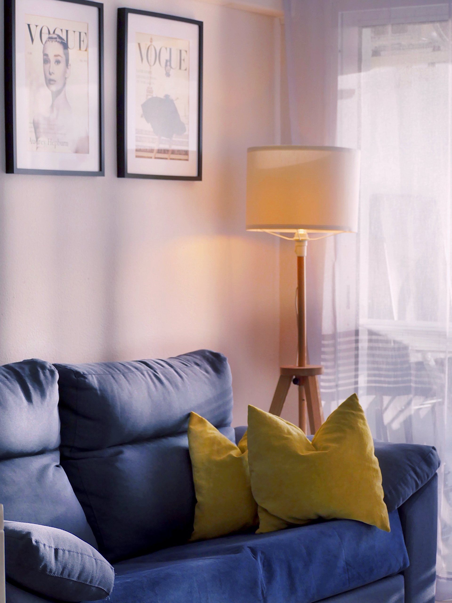 Blue sofa with cushions, floor lamp and framed prints