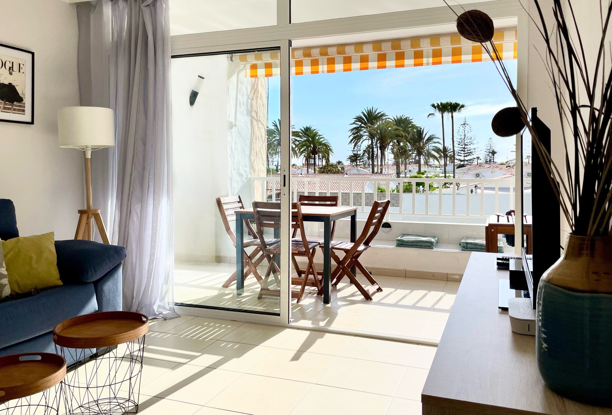 Loggia with table and chairs and palm trees beyond, seen from the living room