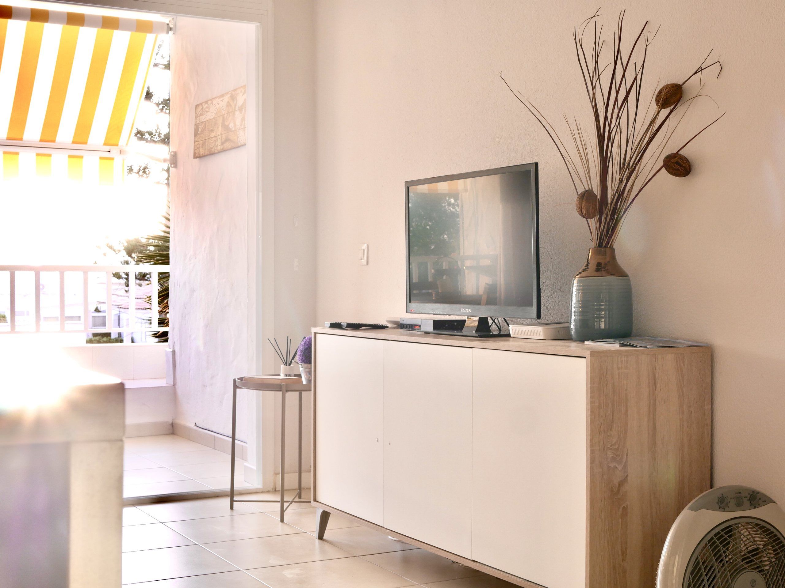 Flat-screen TV on a white cabinet next to the loggia door